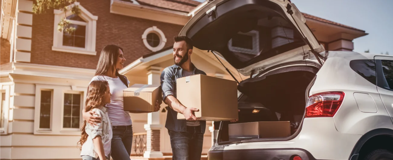 Family unpacking their car while moving into a new Massachusetts home