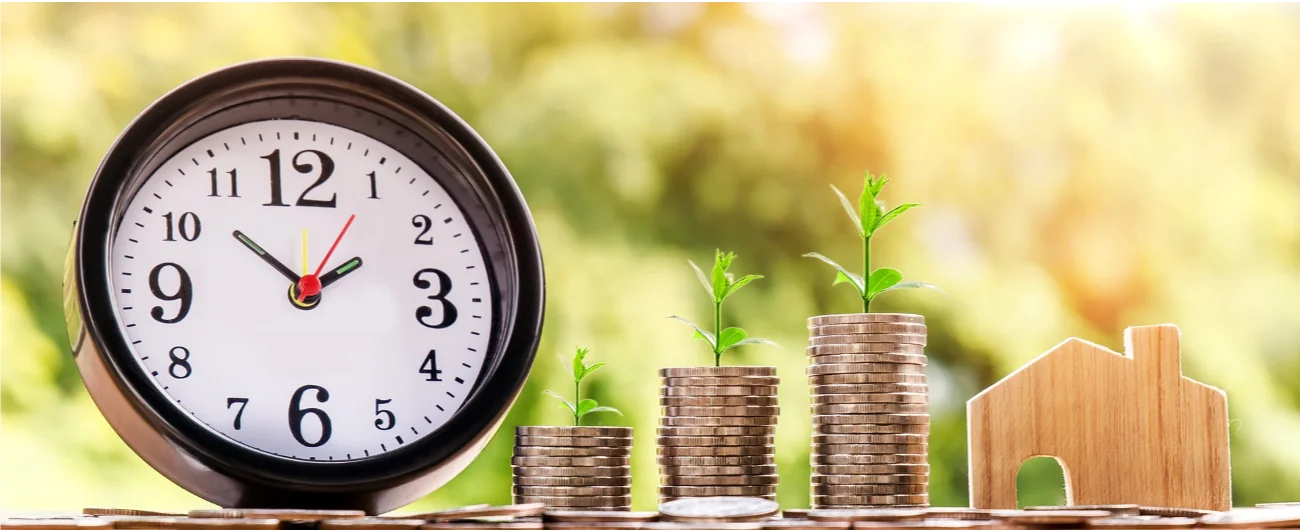 Growing coin stacks beside a small house and clock